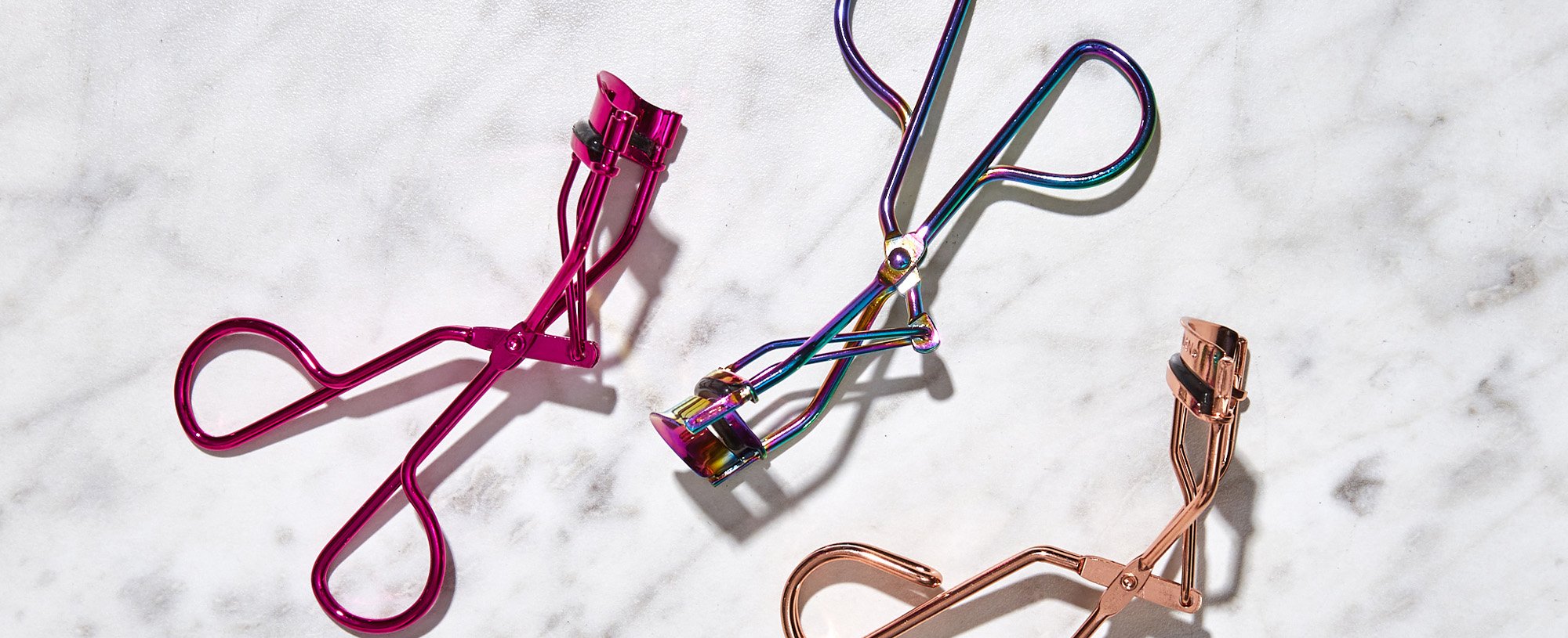 Three Eyelash Curlers On A Marble Surface