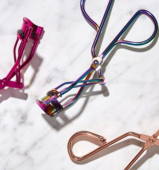 Three Eyelash Curlers On A Marble Surface